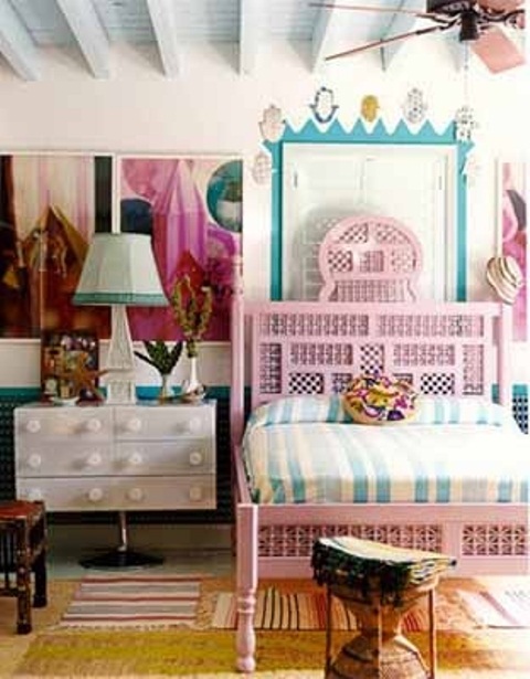 a carved pink bed and a rattan stool give a slight Moroccan feel to the bedroom