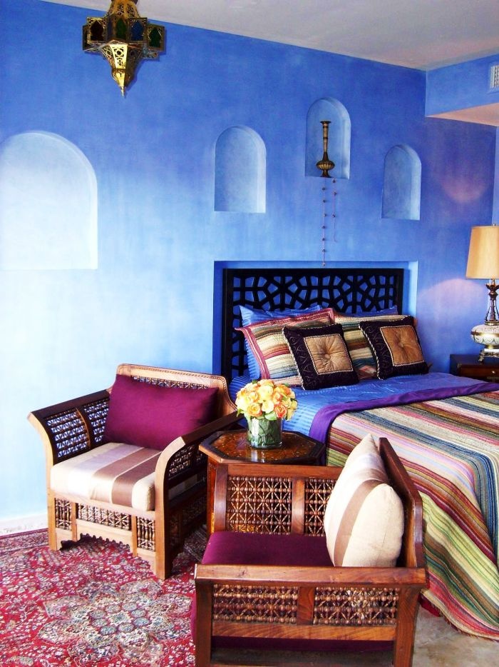 A carved bed and chairs, a Moroccan lantern and colorful printed textiles