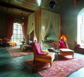 an ornate ceiling, bright textiles and rugs, metlalic lanterns and a bed with a tall frame
