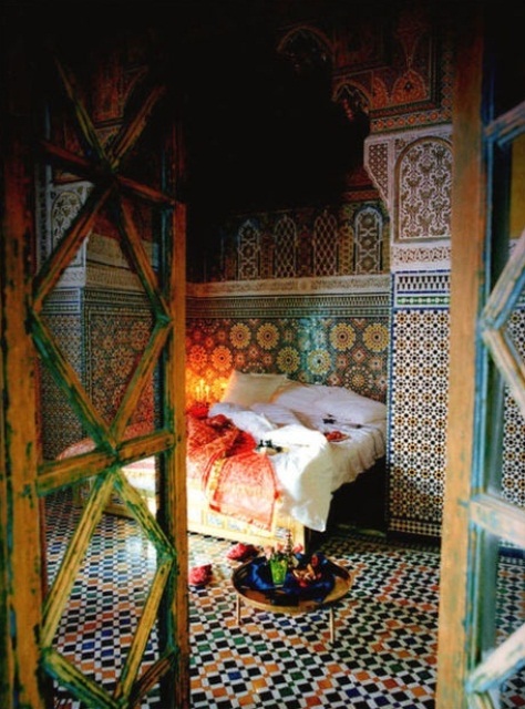 A colorful bedroom fully clad with bright mosaic tiles, a low table and lots of candles feels totally Moroccan like