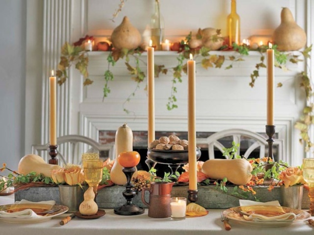 A warm colored tablescape with bright squashes, bold candles, leaves and some matching blooms is chic and cozy