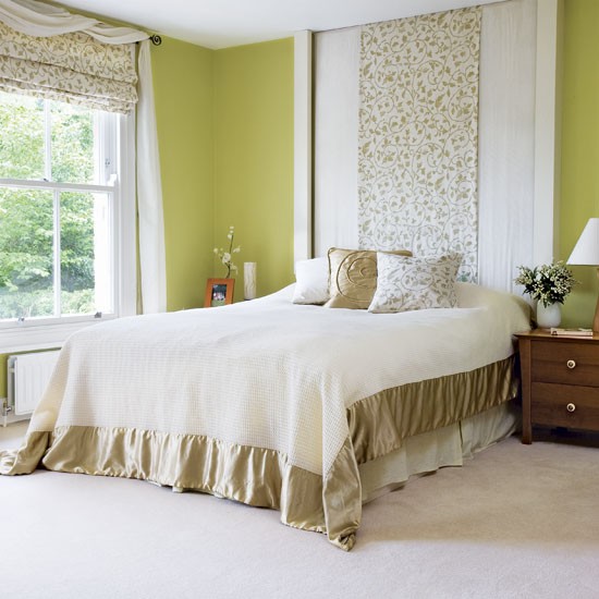 a mustard bedroom with printed curtains and an extended headboard, a bed with chic neutral bedding and dark stained nightstands