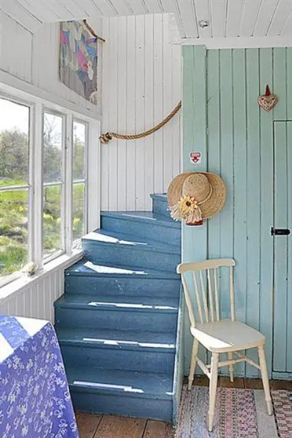 a blue staircase and a mint green wall plus rope railing for a lovely coastal home