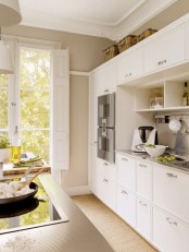 a modern white kitchen with sleek cabinets, a kitchen island, metal countertops and a backsplash and some baskets for storage