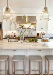 an elegant neutral kitchen with shaker cabinets, a large kitchen island, stainless steel appliances and pendant lamps is amazing