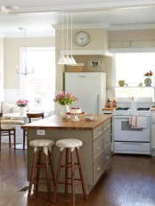 a neutral farmhouse kitchen with butcherblock countertops, pendant lamps, stools and white appliances