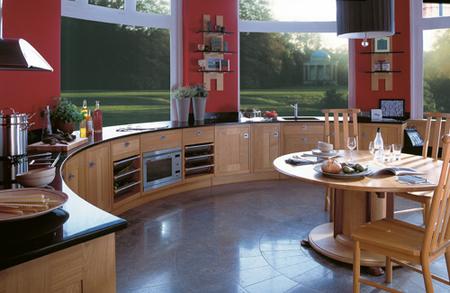 a curved kitchen with wooden cabinets, black coutnertops and red walls plus a gorgeous view is a fabulous place