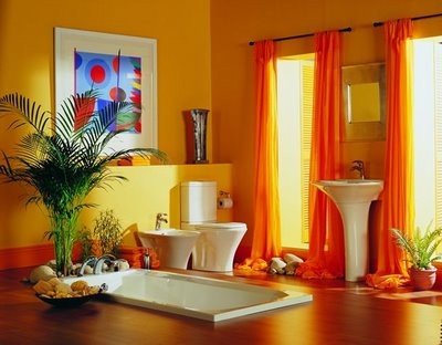 A warm colored bathroom with orange curtains and an orange stripe that connects dark stained floors and warm colored walls