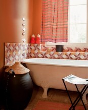 rust-colored walls, bright geometric tiles with rust and burgundy touches, orange striped curtains and a rug