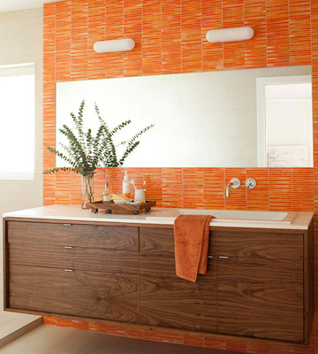 a bright orange tile wall is accents the dark stained wooden vanity and makes it stand out a lot