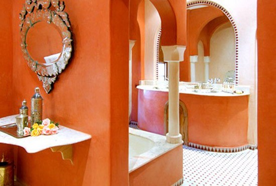 a Moroccan style bathroom with an orange vanity, walls and bathtub cover and refreshing white touches here and there