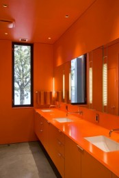 an all-orange bathroom calmed down with a simple concrete floor will flood you with color and brightness