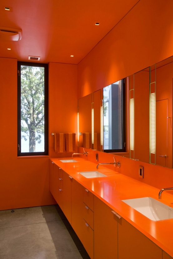 An all orange bathroom calmed down with a simple concrete floor will flood you with color and brightness