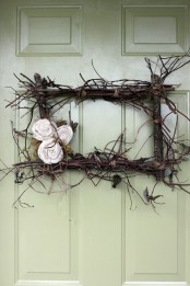 a twig and stick rectangle wreath with moss and fabric blooms is a cool decoration that will make the porch look vintage