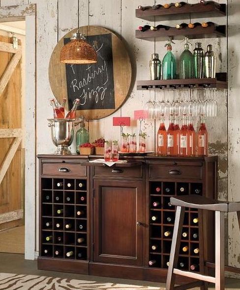 A dark stained rustic home bar with a large storage unit and some open shelves, a chalkboard menu and other pretty decor for a vintage rustic space