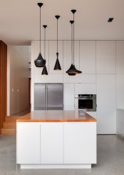 a cluster of gorgeous mismatching matte black pendant lamps is a lovely idea for a contemporary or minimalist kitchen