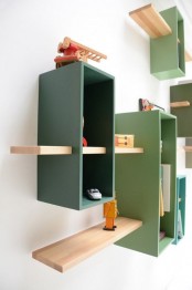 a wall-mounted bookcase in muted green shades with natural-colored shelves features much storage space in a creative way