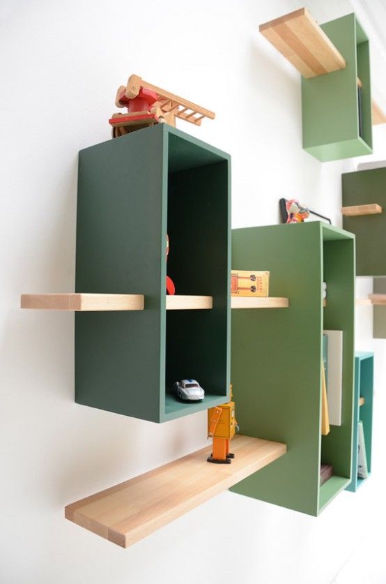 A wall mounted bookcase in muted green shades with natural colored shelves features much storage space in a creative way