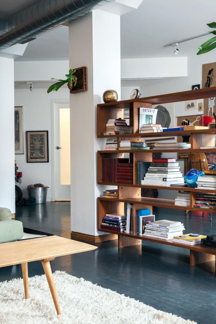 A rich stained wood bookcase made of long boxes doubles as a space divider without looking bulky