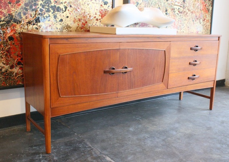 A rich stained sideboard with catchy carved doors and drawers with elegant handles is a lovely idea to give a mid century modern feel to the space