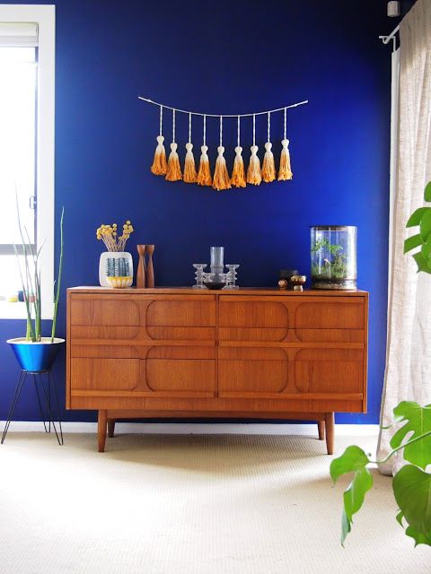 A catchy rich stained sideboard with carved wooden doors on tall legs is a stylish and catchy idea for a mid century modern space