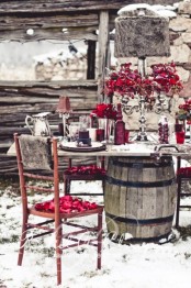 a bright winter tablescape with red blooms, red cranberries, glasses, vases and cozy lamps with felt lampshades