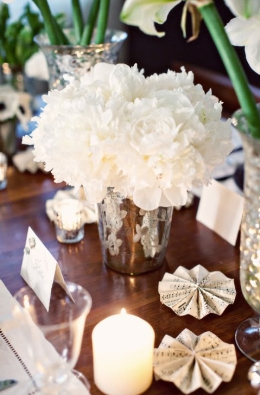 a lush white floral centerpiece in a silver bucket and pillar candles is a chic idea for a winter table setting