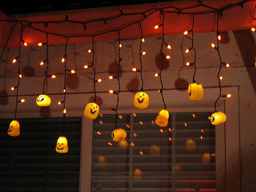 Cover some string lights with orange tissue paper balls with scary faces for a beautiful glowing display.