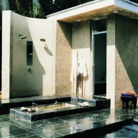 a simple contemporary bathroom outdoors with a shower and a built-in bathtub all clad with green tiles