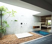 a contemporary outdoor shower with a concrete wall, pebbles and greenery