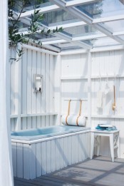 a seaside inspired outdoor bathroom done with beadboards, a blue tub and some accessories plus blue towels