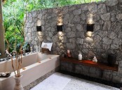 a natural space with a stone wall, a large bathtub, a shelf and built-in features