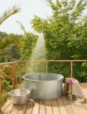 a rustic outdoor bathroom with a metal bathtub and some smaller tubs for storage