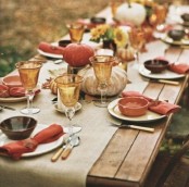 a simple Thanksgiving table with a burlap table runner, red napkins, amber glasses, pumpkins on wood slices