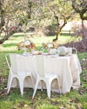 a pale tablescape with neutral heirloom pumpkins and neutral bloom centerpieces for Thanksgiving