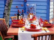 a bold Thanksgiving table setting with bright red plates and placemats, candles and a white table runner