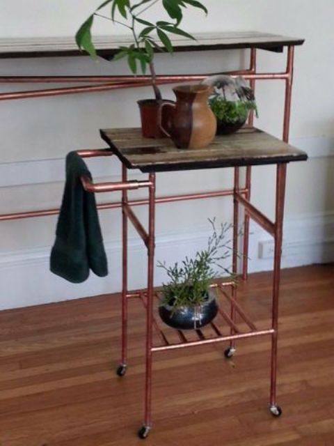 Tables made of copper pipes and dark stained wood are a great idea for an industrial or modern space, potted plants refresh the look