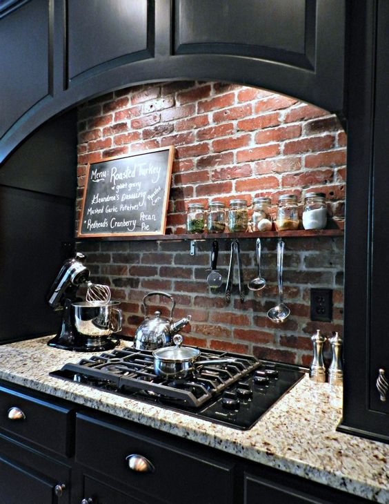 a black vintage kitchen with shaker style cabinets, stone countertops and a red brick backsplash create a bold and contrasting look