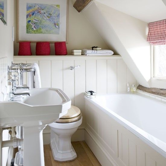 a small creamy attic bathroom done with beadboards, a free-standing sink and touches of red