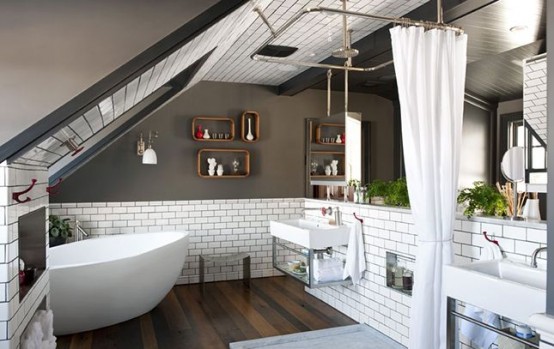 an industrial-inspired attic bathroom with grey walls, white subway tiles, an oval tub, a shower space and two sinks 