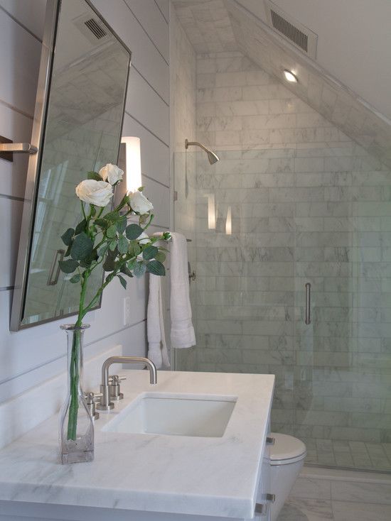 a small marble attic bathroom with a square marble sink and a small shower space 