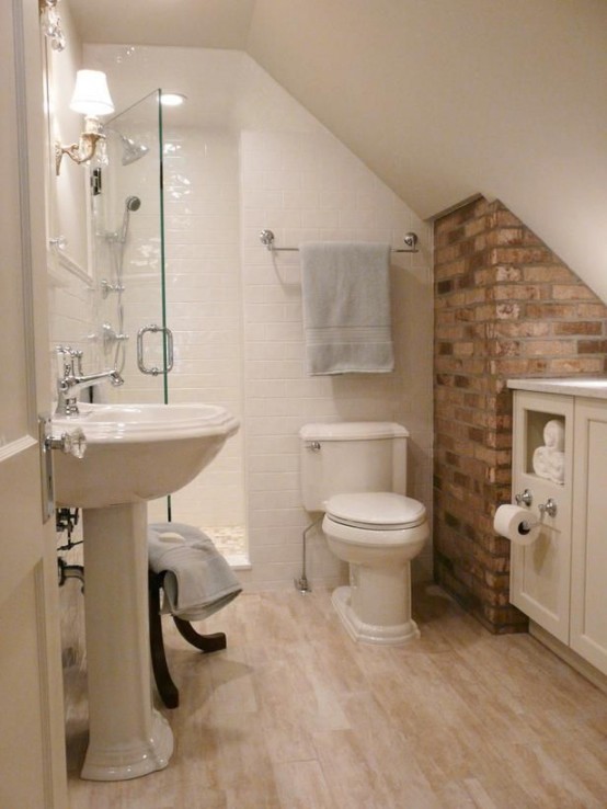 a small attic bathroom with a brick wall, white tiles, a free-standing sink and a floating vanity