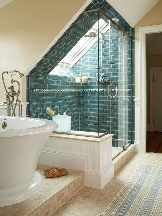 an attic bathroom with a shower space clad with blue tiles and a refined bathtub and a striped rug