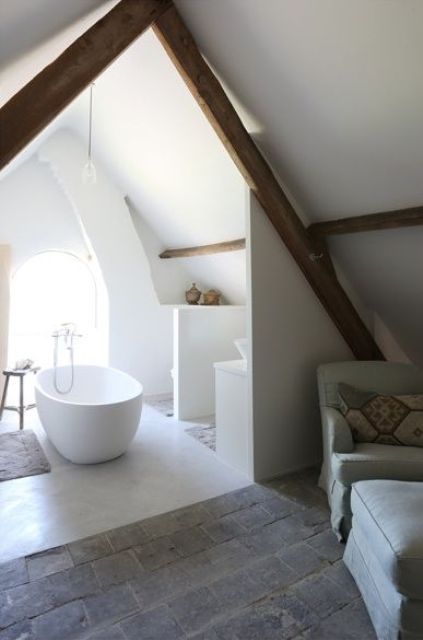 a small white attic bathroom with wooden beams, a tub and some shelves for storage