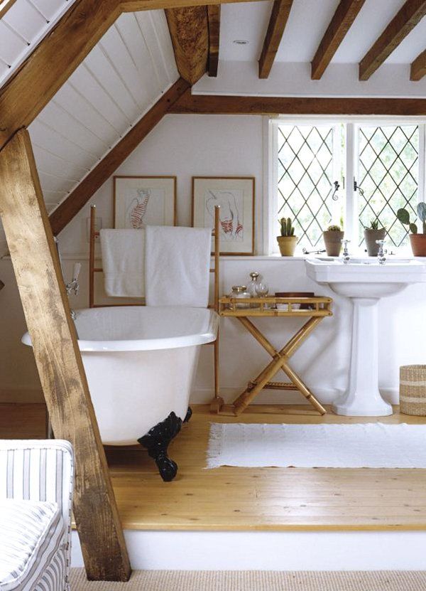 an attic rustic bathroom with wooden beams, a clawfoot tub, a free-standing sink and wooden furniture