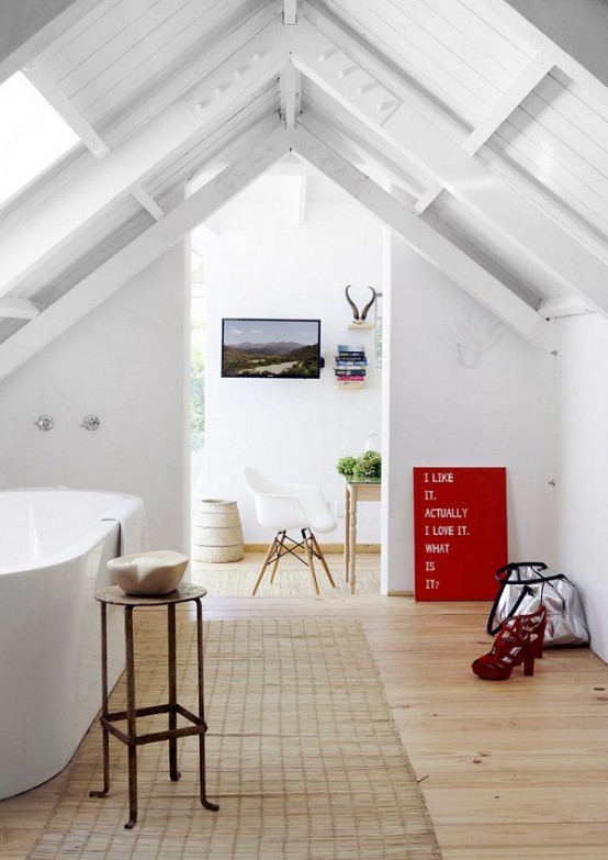 a white attic bathroom with an oval tub, some furniture and a jute rug, the space is flooded with light