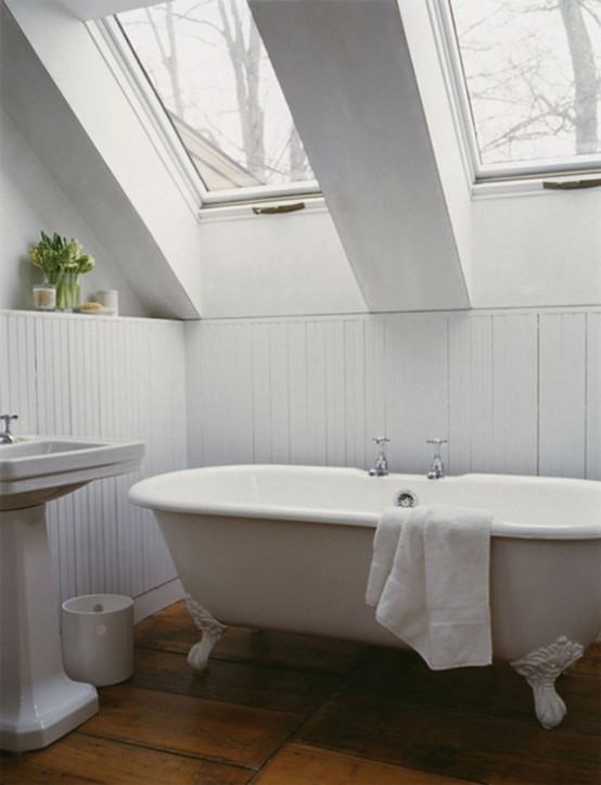 a white attic bathroom with skylights, a free-standing sink and a clawfoot tub