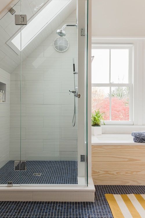 a shower space with navy tiles, a large storage unit under the windowsill