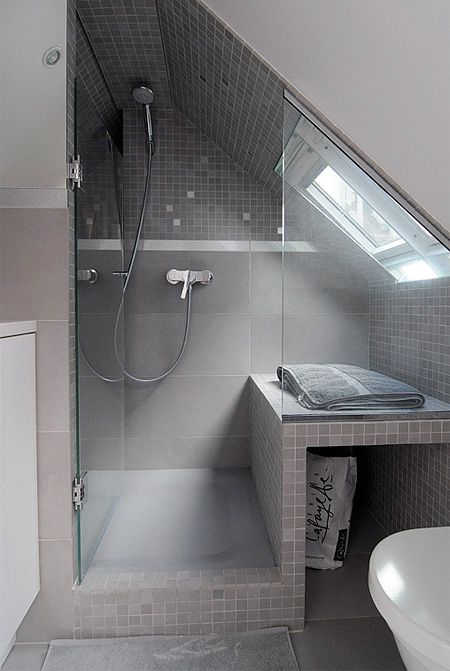 a neutral small attic bathroom with a skylight in the shower, grey and taupe tiles