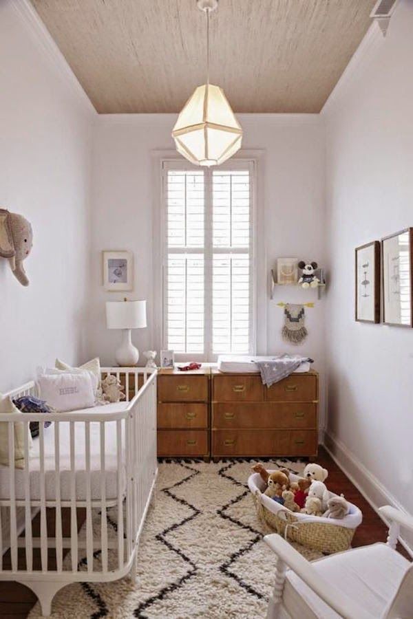 A neutral mid century modern nursery with a stained dresser, a white crib, a printed rug and some toys in baskets is a cool idea